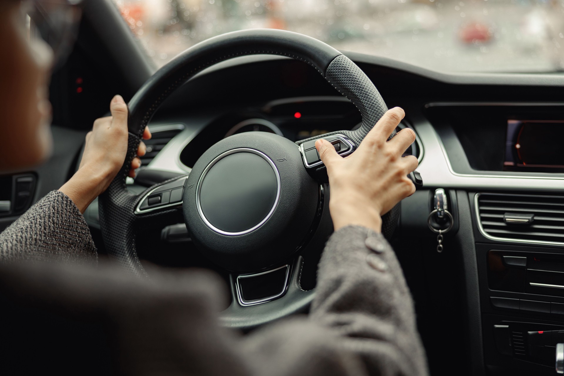 Back view of woman driver pushes the button on steering wheel during drive
